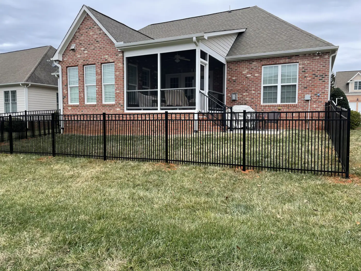 Black aluminum fence running the rear perimeter of a brick ranch home with a screened porch near Cary, NC