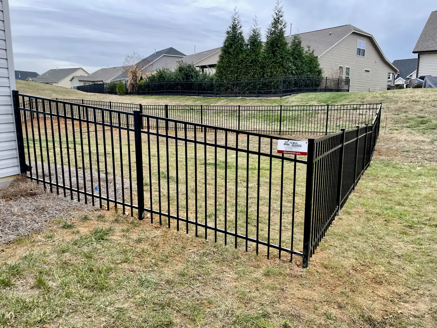 Black aluminum fence corner enclosing a new subdivision backyard