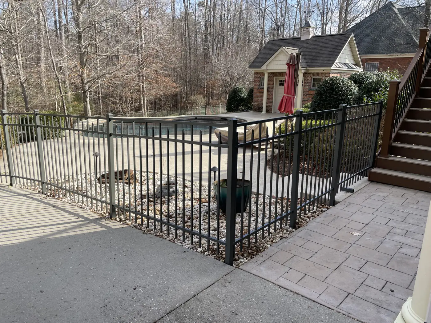 Black aluminum pool fence enclosing an in-ground pool and patio