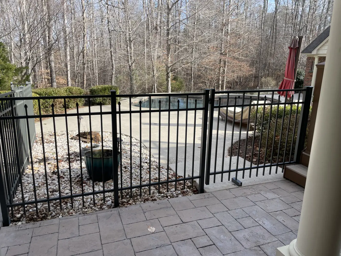 Black aluminum pool gate beside a paver patio