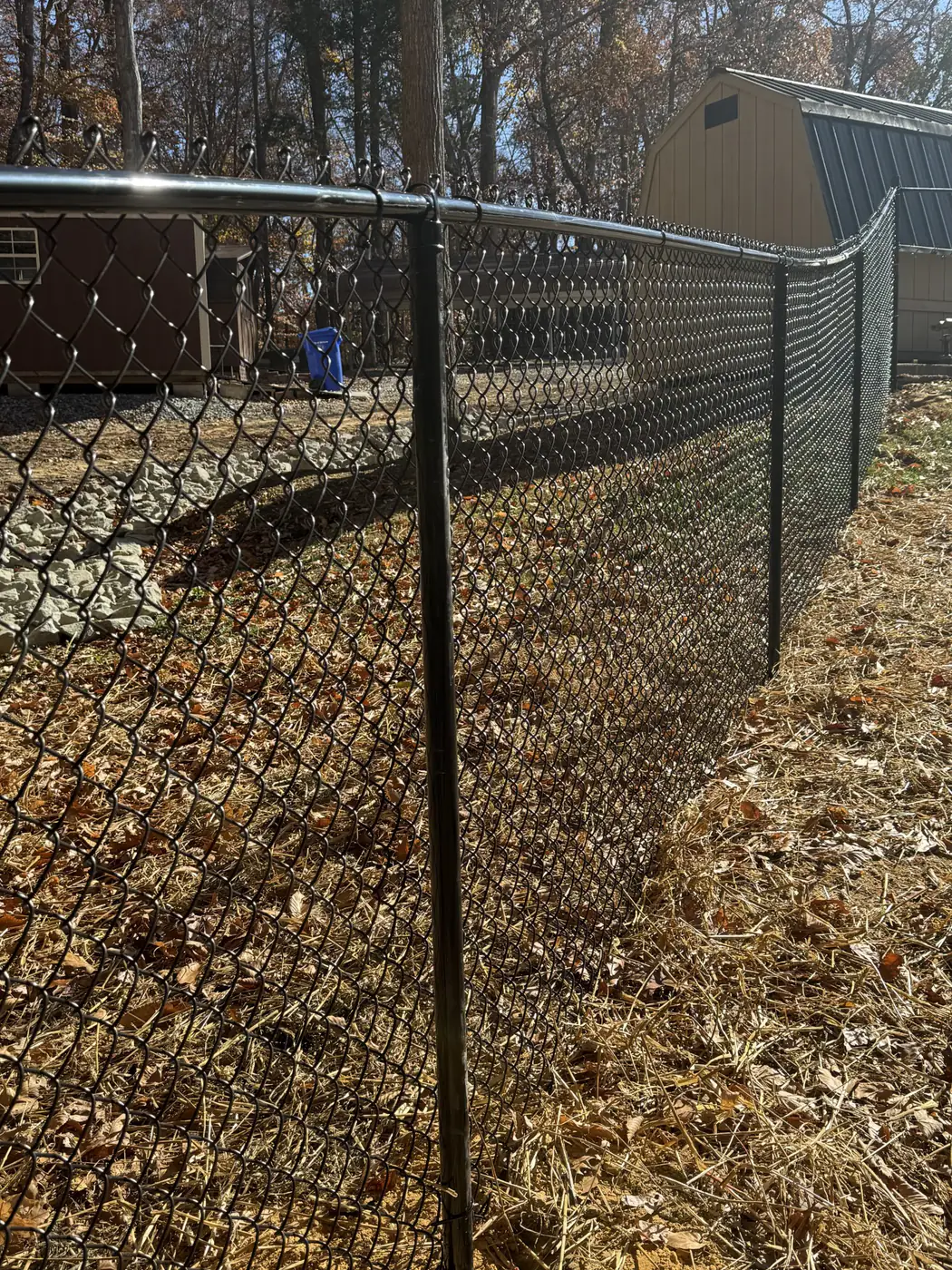 Black-coated chain link fence securing a storage shed perimeter