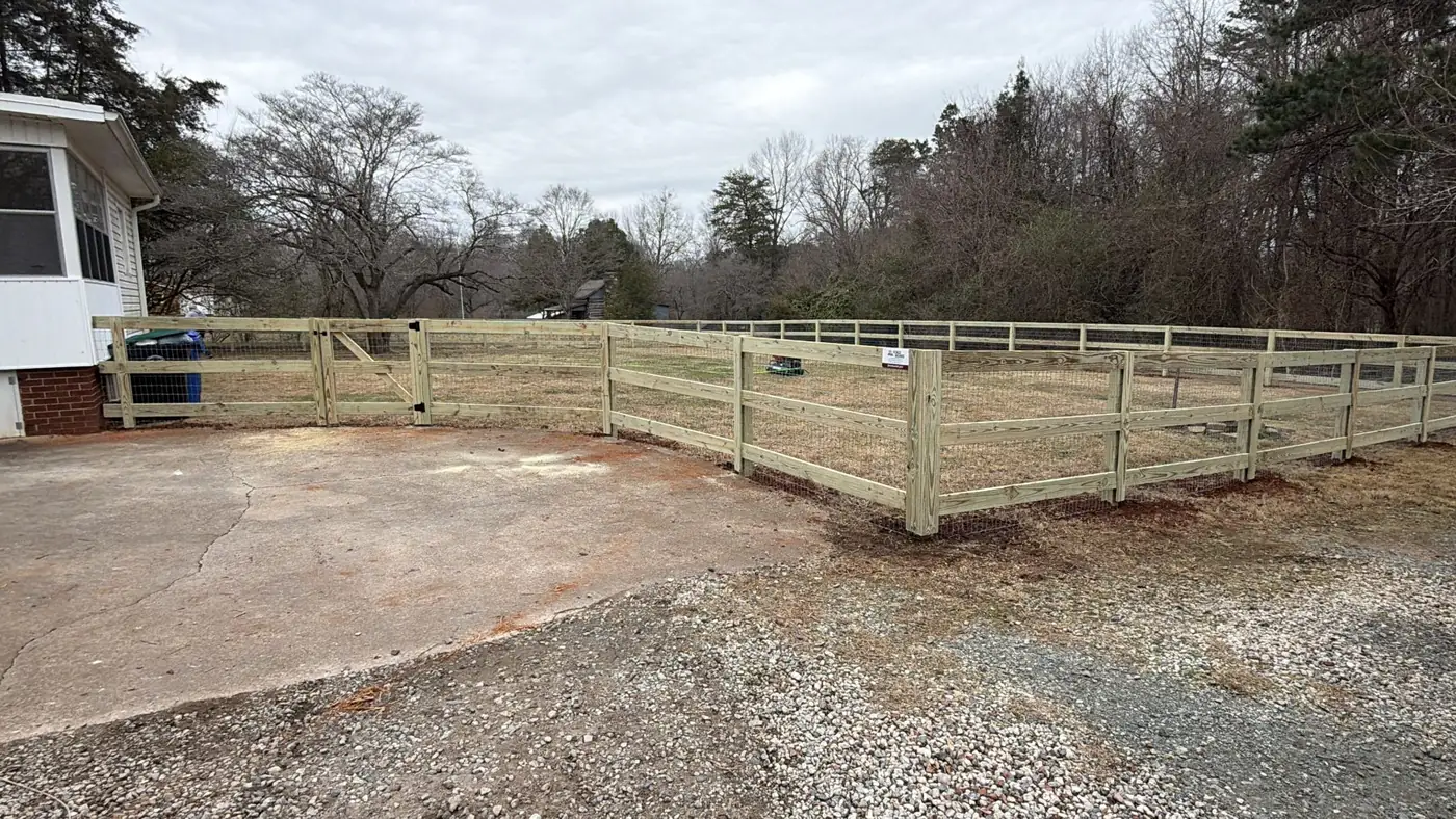 Wood ranch rail fence with a driveway gate along a gravel drive