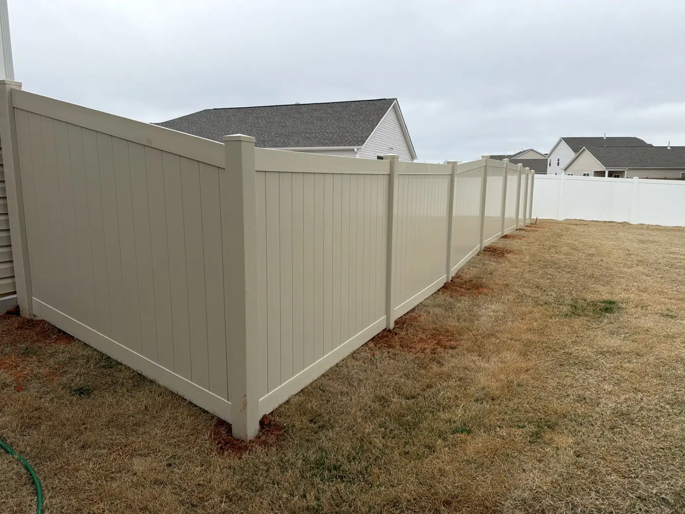 Tan vinyl privacy fence enclosing a subdivision backyard near Graham, NC