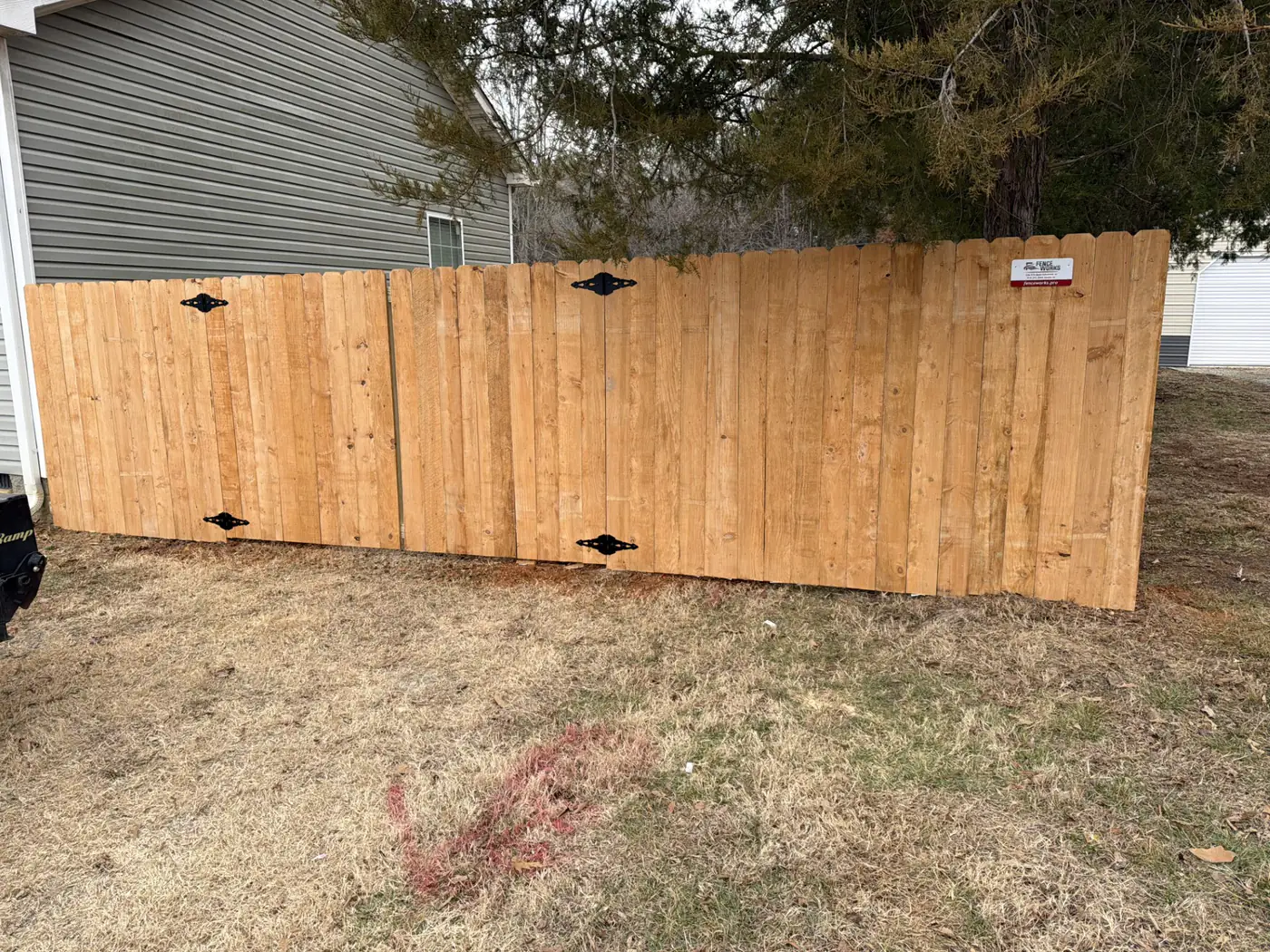 Wood privacy fence with a double drive gate and heavy black hardware