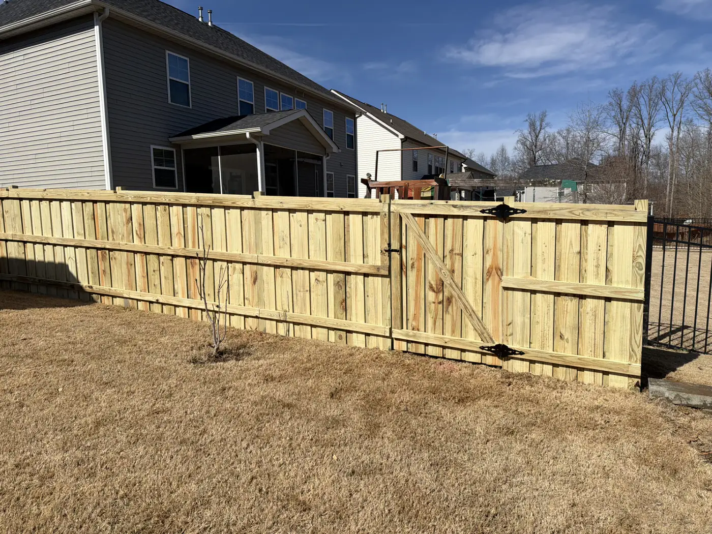 Wood privacy fence with a walk gate across a residential backyard