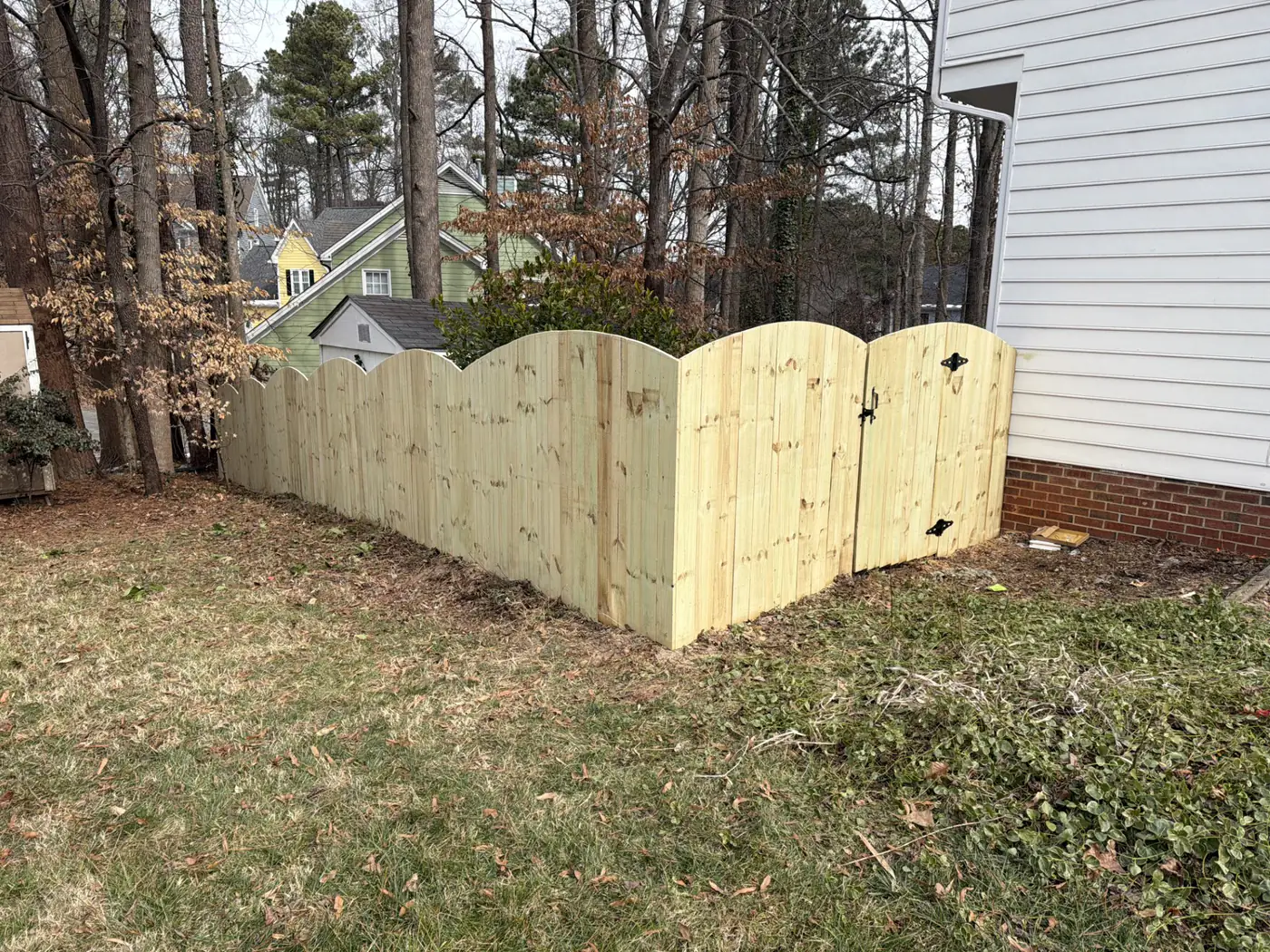 Scalloped-top wood privacy fence with a custom double gate between two homes